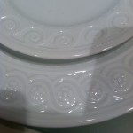 White china plate with border of curling lines